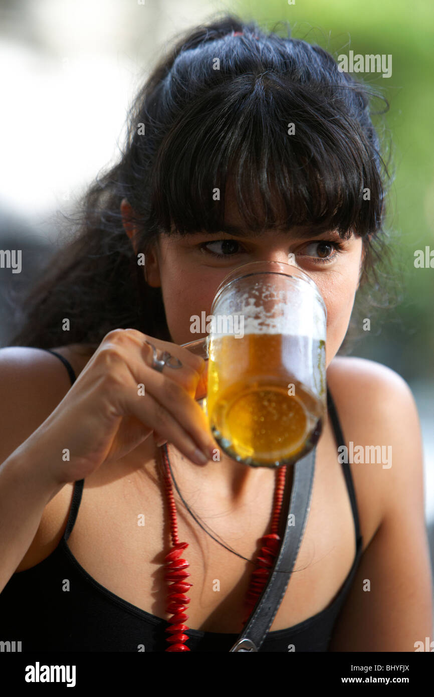 Mitte der zwanziger Jahre hispanic Frau trinkt ein Glas Bier in einem Café im freien Tisch Stockfoto