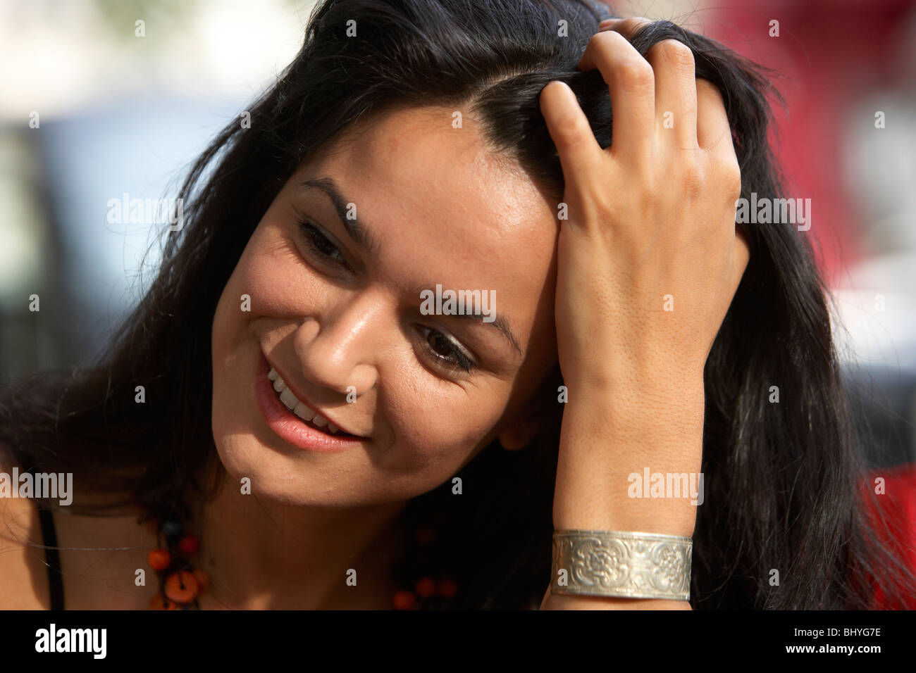 Mitte der zwanziger Jahre hispanic Frau lächelnd mit den Fingern durch ihr Haar Stockfoto
