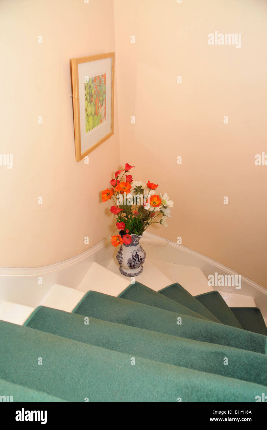 Reich verzierte Vase mit roten Blumen schmücken ein Teppichboden Treppenhaus. Stockfoto