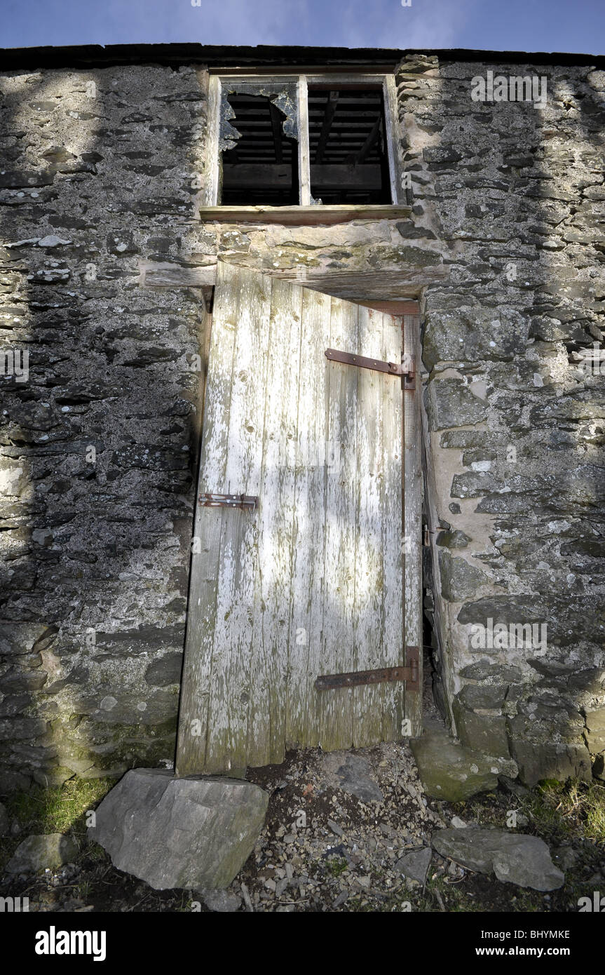 Walisische unheimliche Scheune mit Baum Schatten zerbrochenes Fenster und Holztür Stockfoto