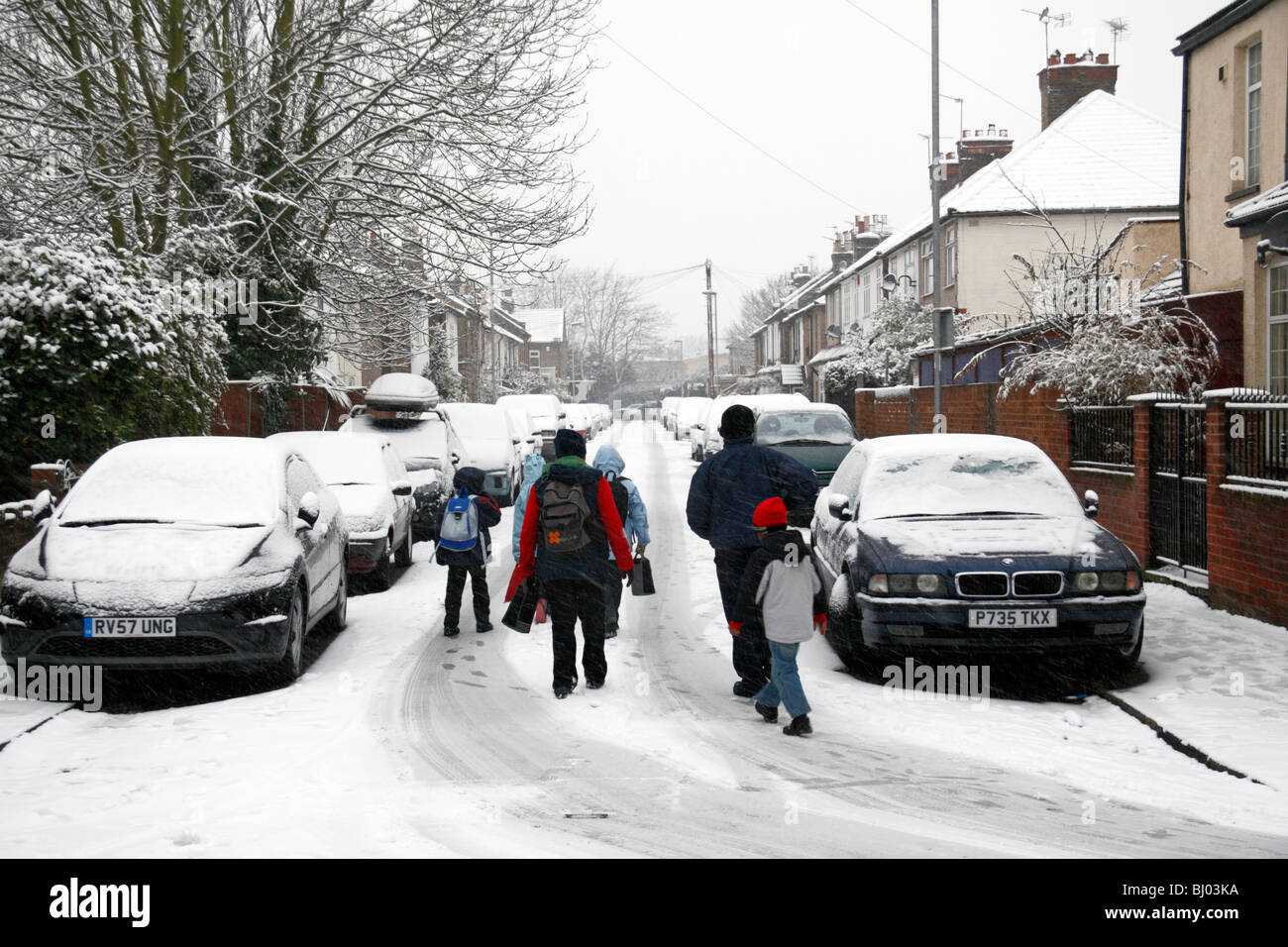 Eine Familie, die zu Fuß zur Schule, eine Schnee bedeckt Straße in Hounslow, westlich von London, im Winter 2009/10. Stockfoto