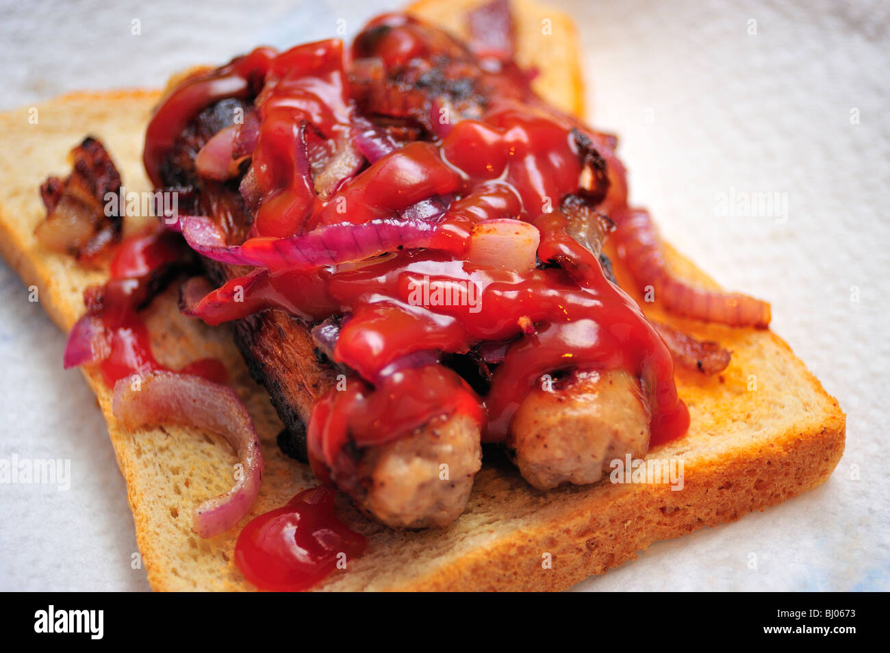 Würstchen auf Toast mit Zwiebeln und Tomatensauce Stockfoto