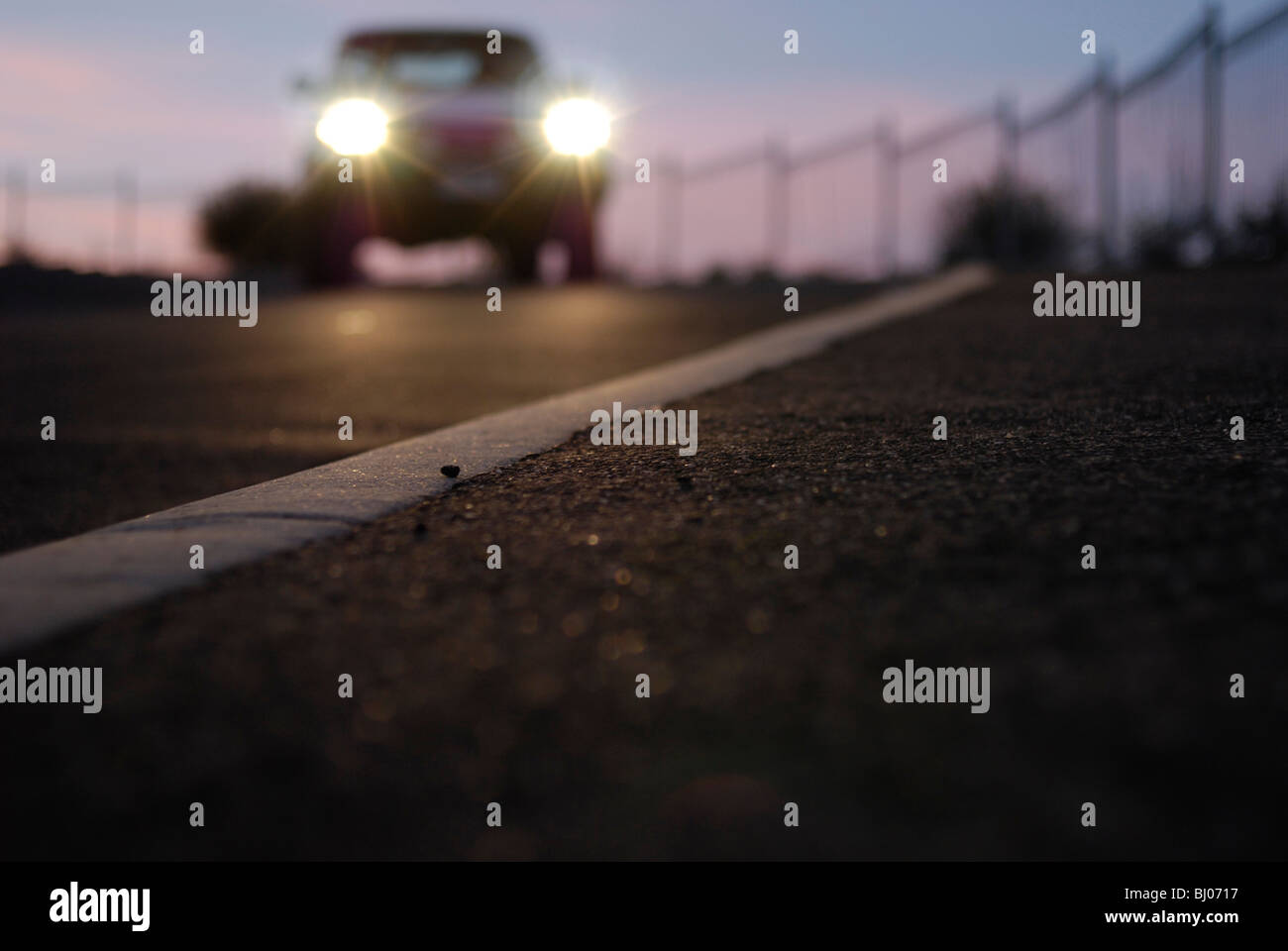 Autoscheinwerfer Runde fahren bücken eines Hügels in der Abenddämmerung. Stockfoto