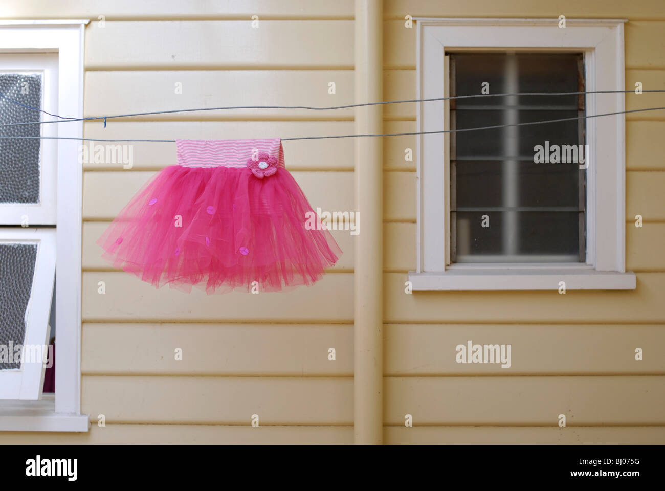 Kleines Mädchen Tutu Ballerina Kleid Wäscheleine vor alten Wetterschenkel Haus hängen. Stockfoto