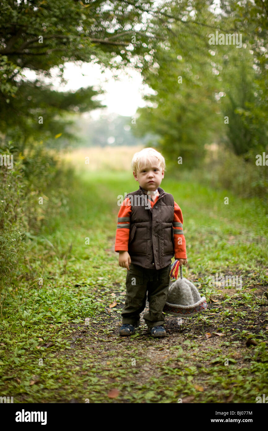 Kleiner Junge hält seine Wintermütze draußen Stockfoto