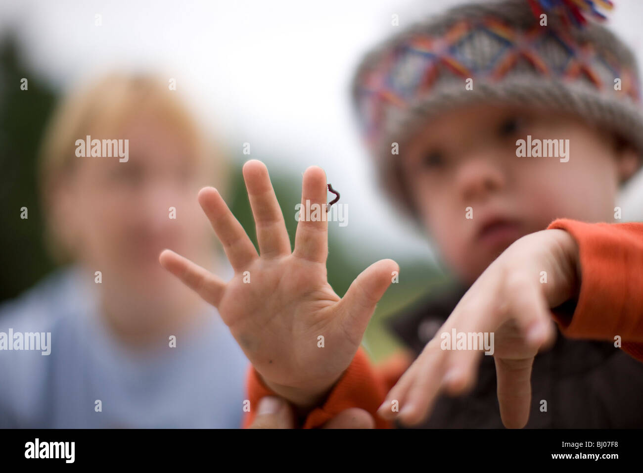 Kleiner Junge eine Raupe kriecht auf seiner Hand zu betrachten. Stockfoto