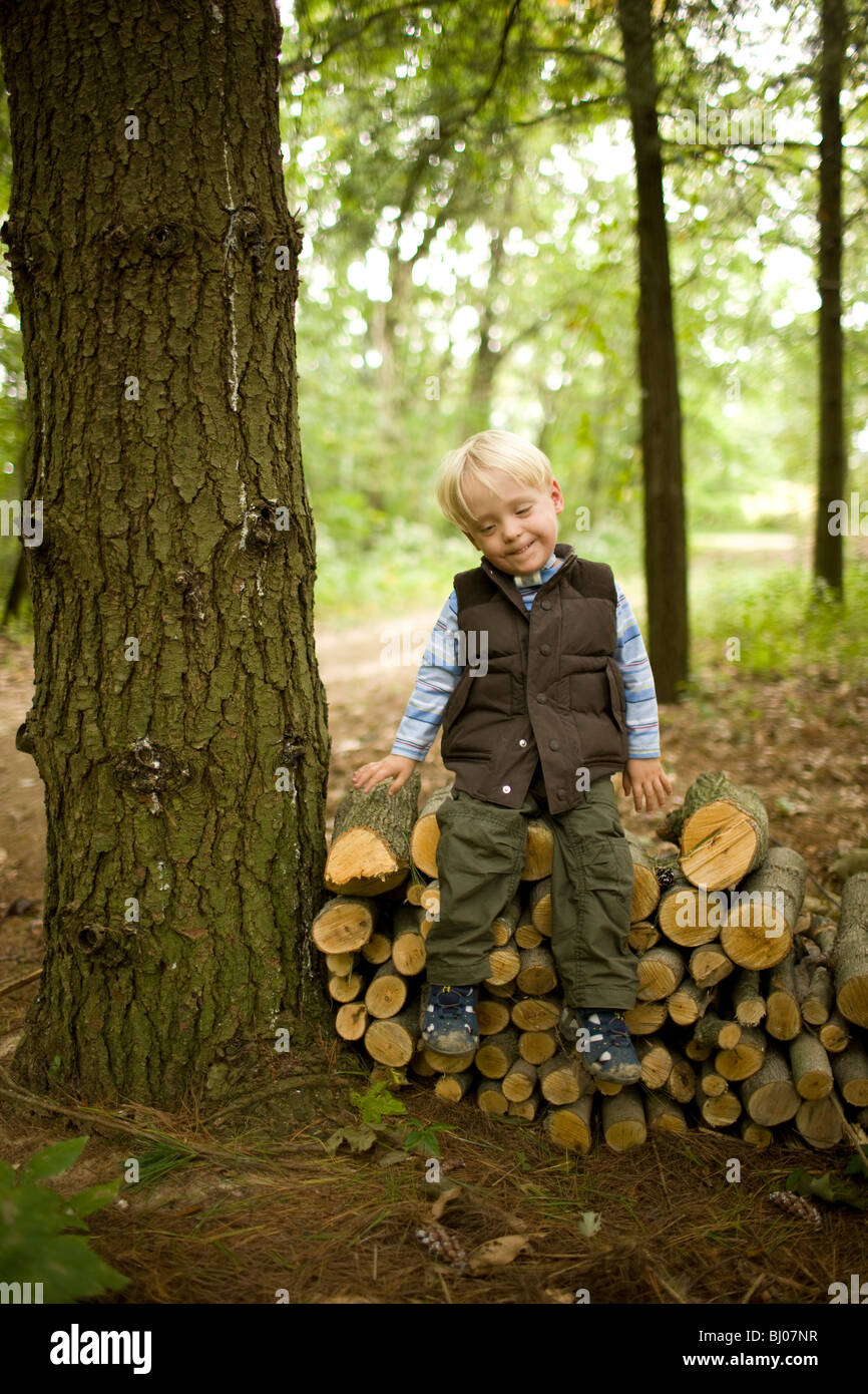 Junge sitzt auf einem Stapel Holz. Stockfoto