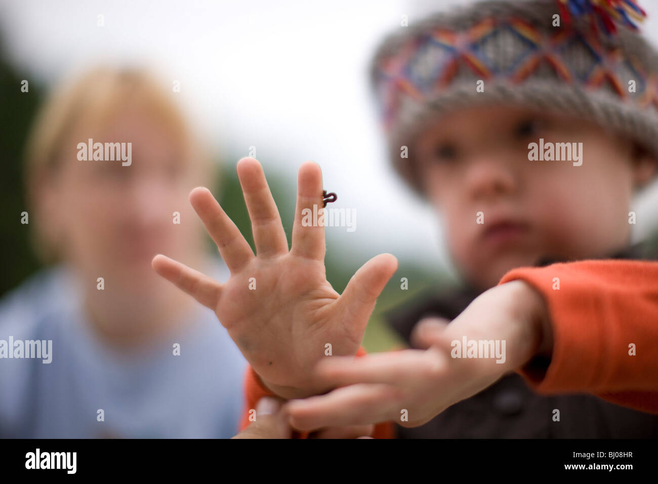 Kleiner Junge eine Raupe kriecht auf seiner Hand zu betrachten. Stockfoto