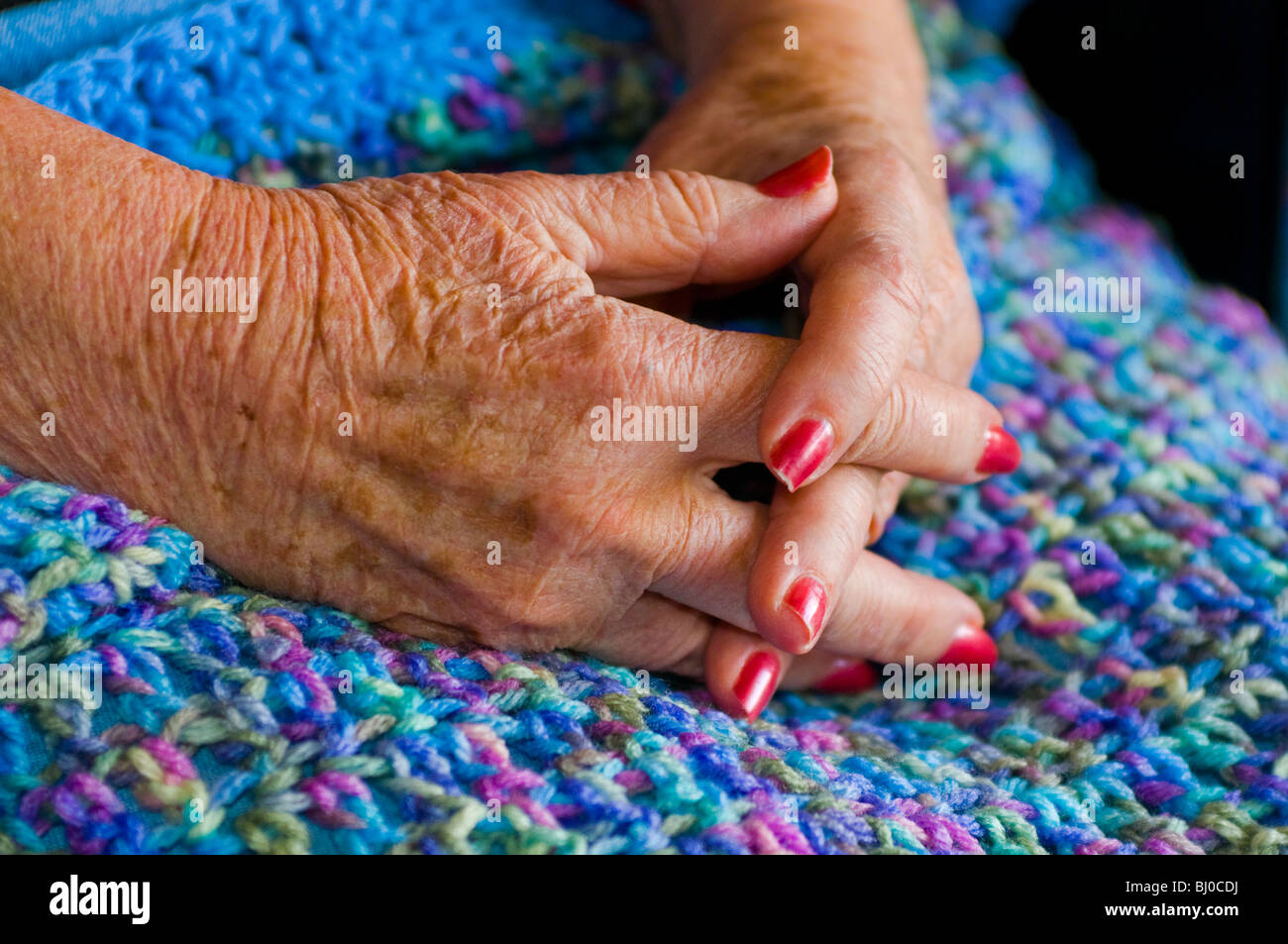 Womans Altern Hände ruhen auf gestrickte Decke. Stockfoto
