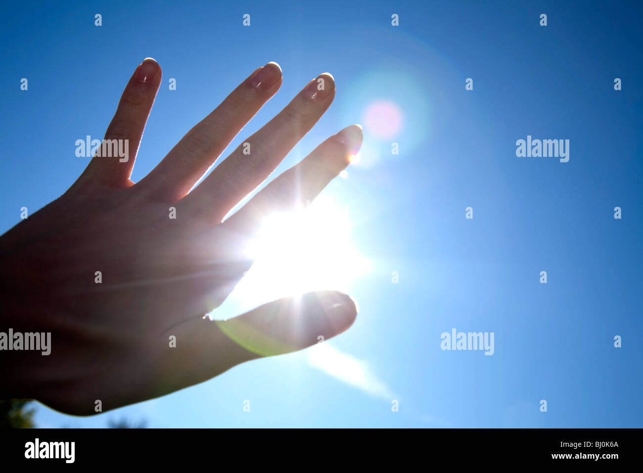 Nahaufnahme der Hand vor blauem Himmel mit brennenden Sonne Stockfoto