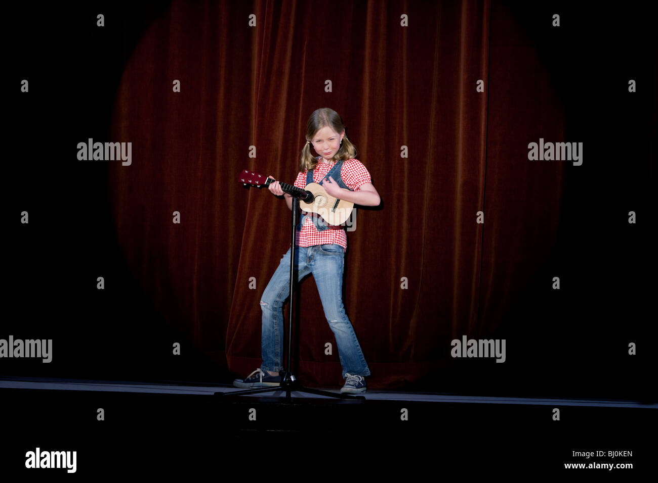 junge Mädchen spielt Gitarre auf der Bühne Stockfoto