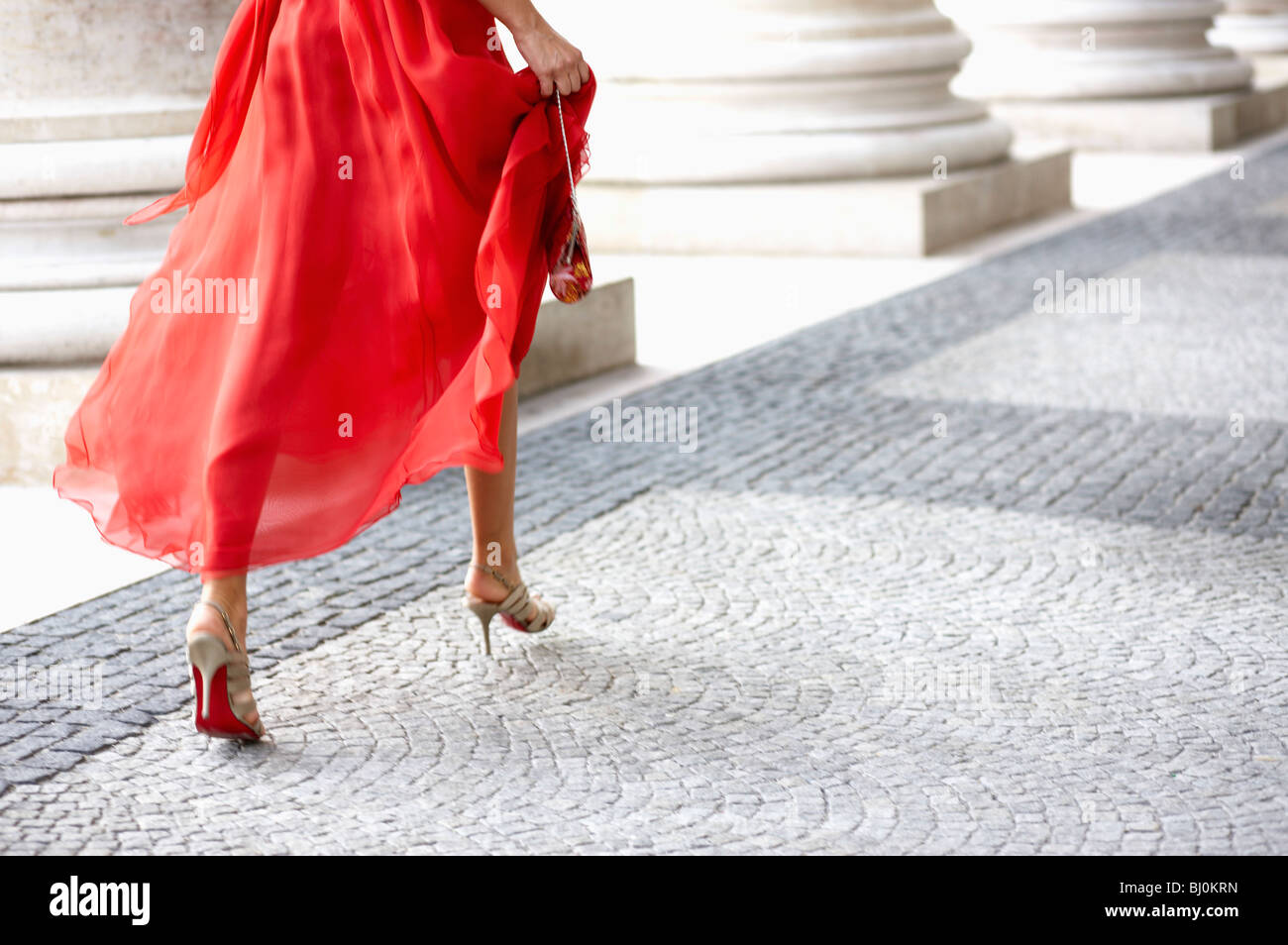 Detail der junge Frau im roten Kleid, die durch Arkaden des Theaters Stockfoto