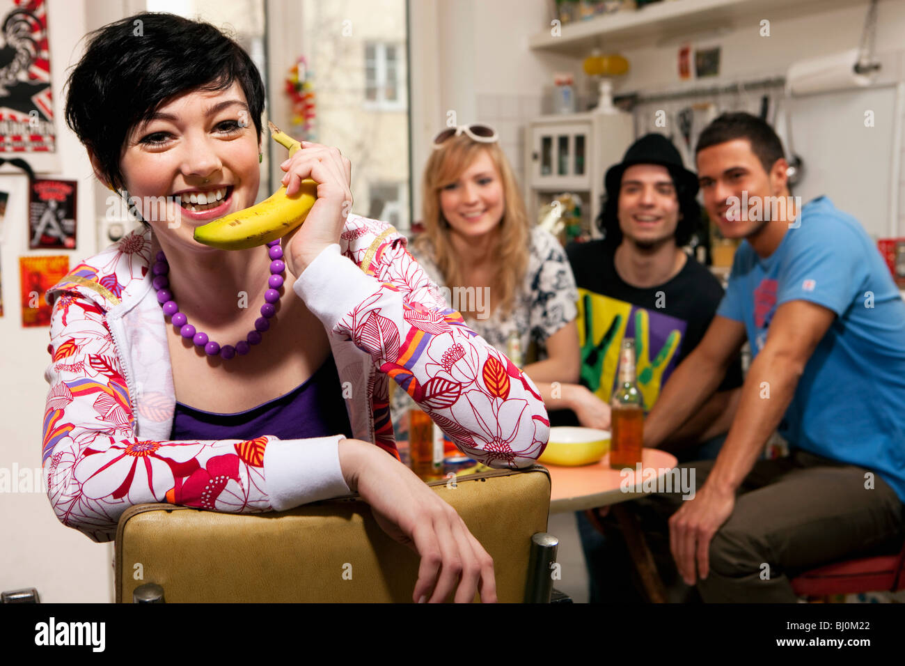 Porträt von Teenager-Mädchen mit Freunden in Küche mit Banane als Telefon Stockfoto