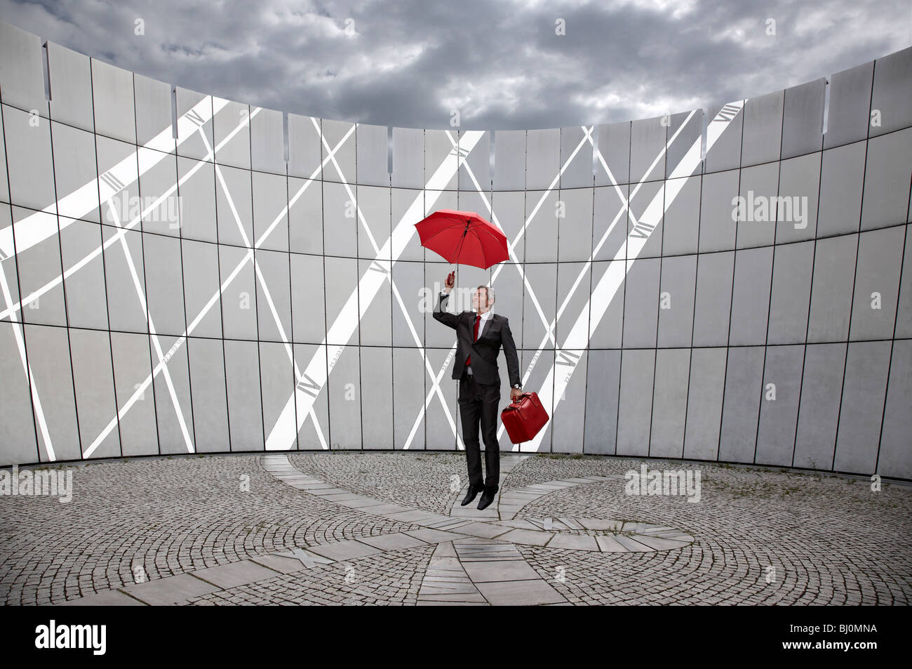 Geschäftsmann mit roten Koffer und Regenschirm springen Stockfoto