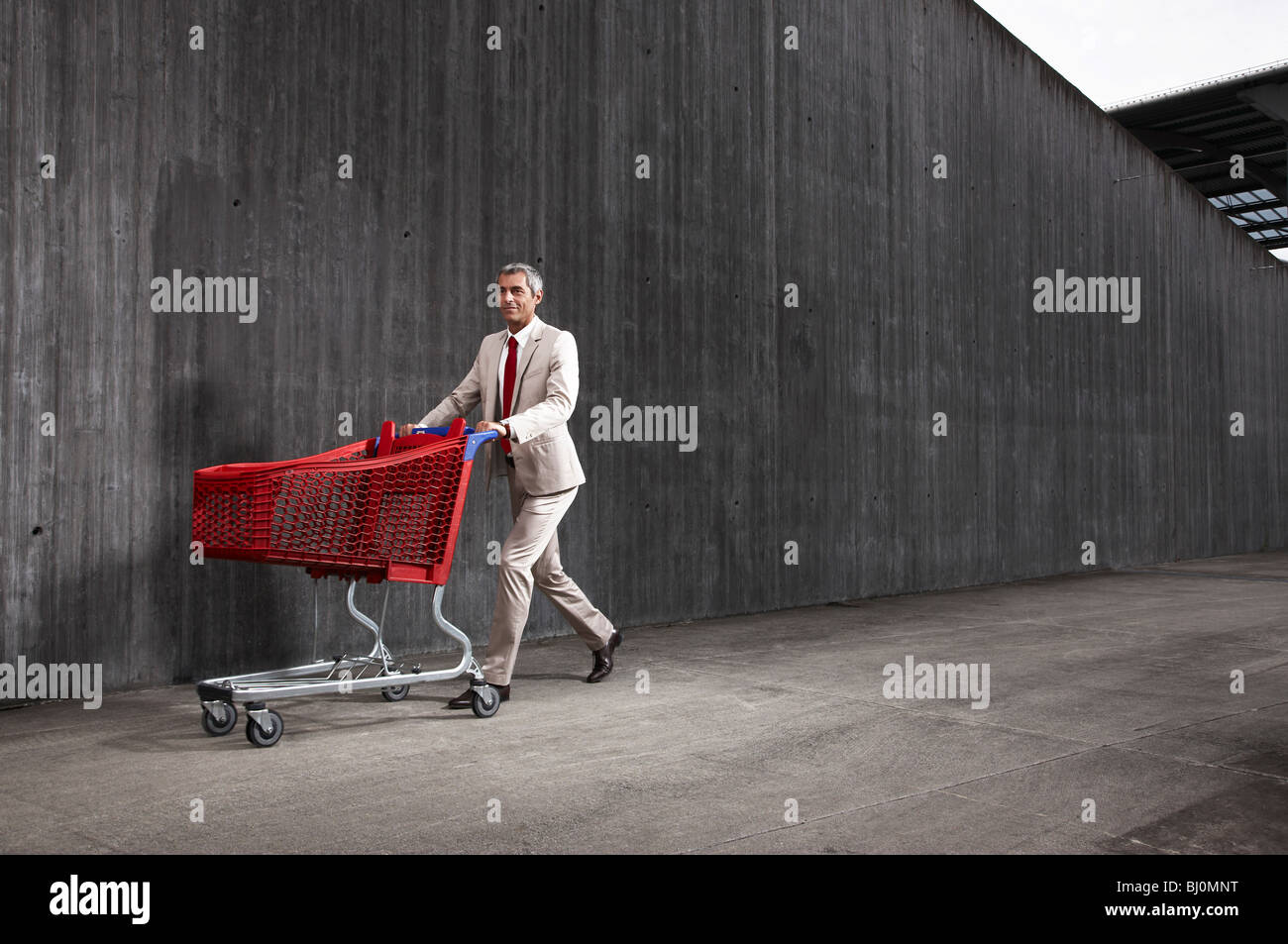 Geschäftsmann, roten Einkaufswagen schieben Stockfoto