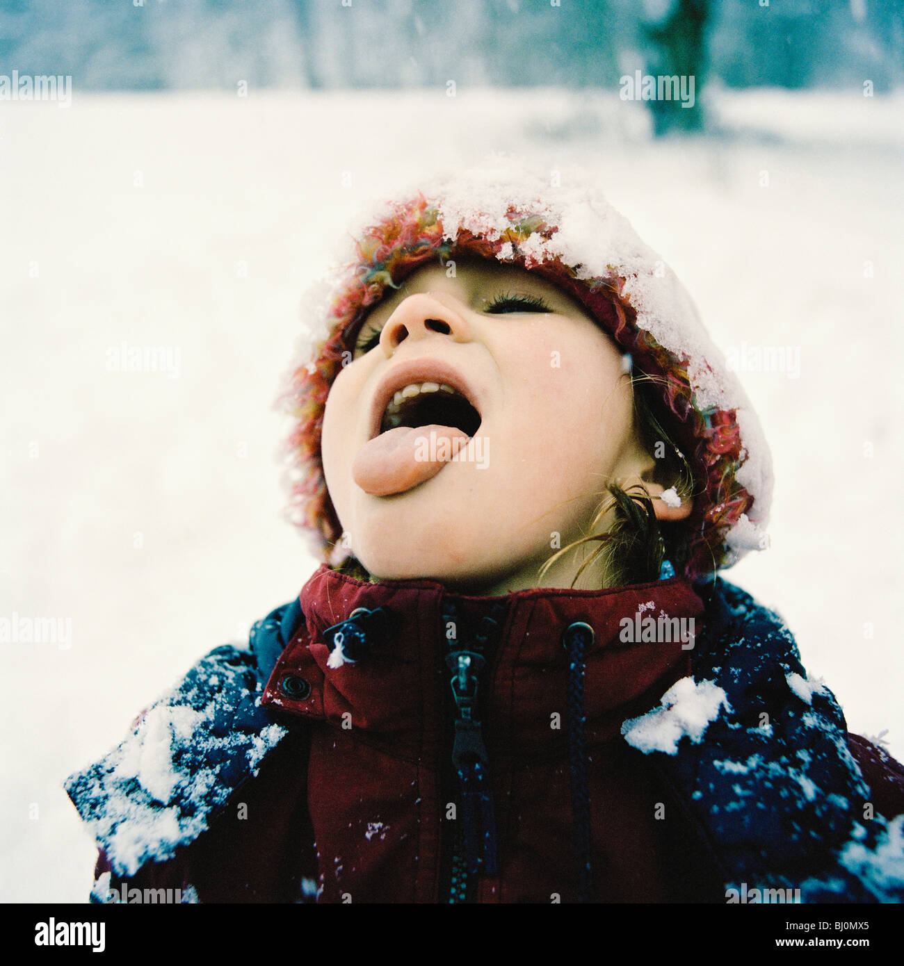 Porträt von kleinen Mädchen im Winter, die Zunge, den fallenden Schnee zu probieren Stockfoto
