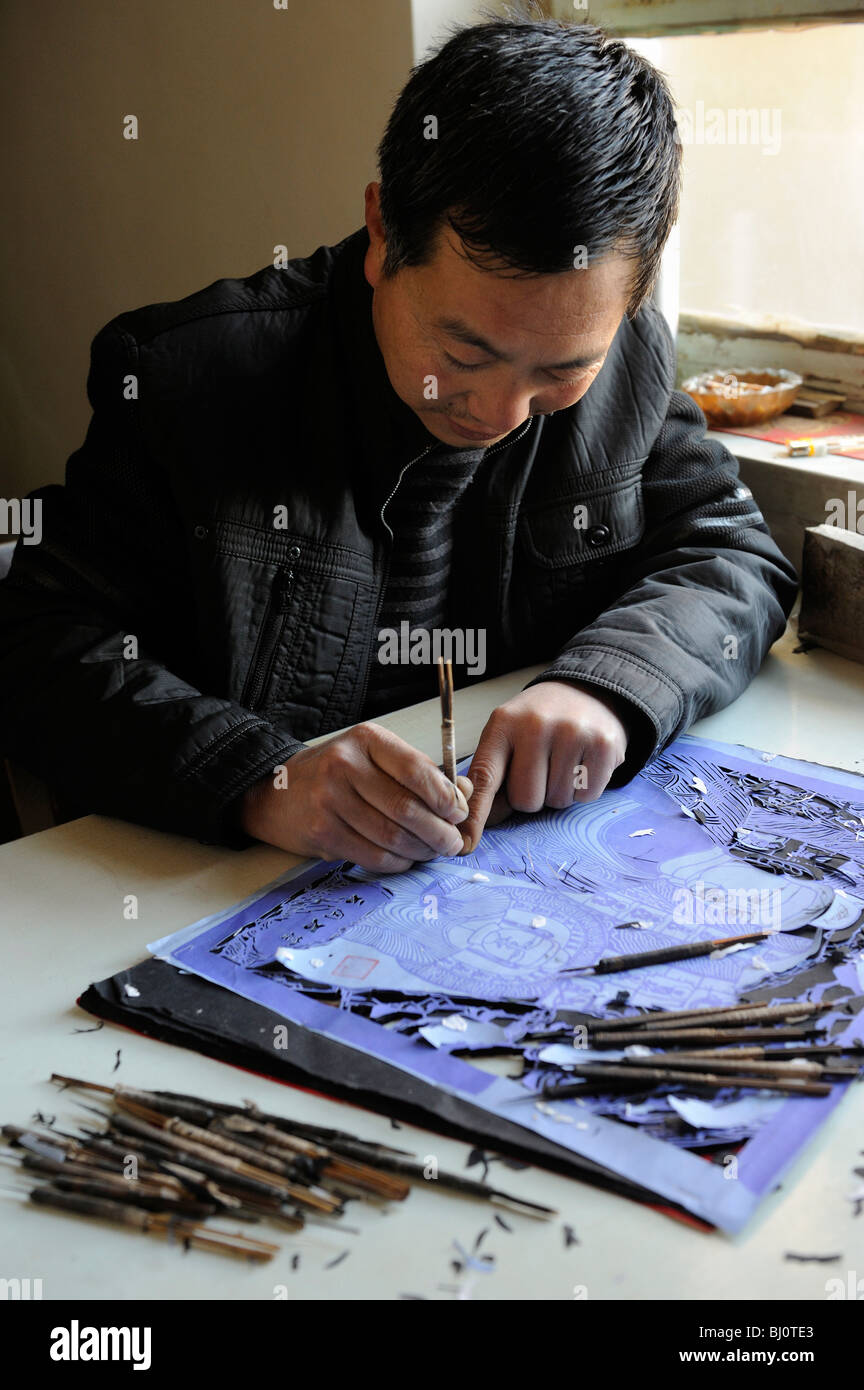 Ling Mande, ein Volkskünstler des Scherenschnitts, arbeitet in seinem Atelier in Yuxian county, Provinz Hebei, China.02-Mär-2010 Stockfoto