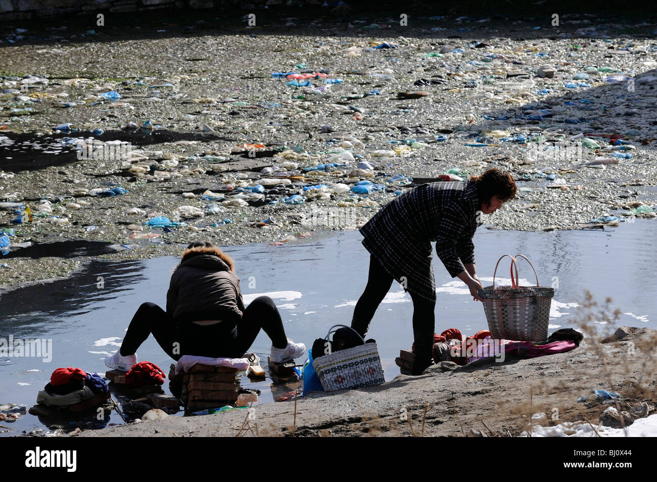 Frauen, die Wäsche in einem verschmutzten Teich in einem Dorf in der Provinz Hebei, China. 2. März 2010 Stockfoto