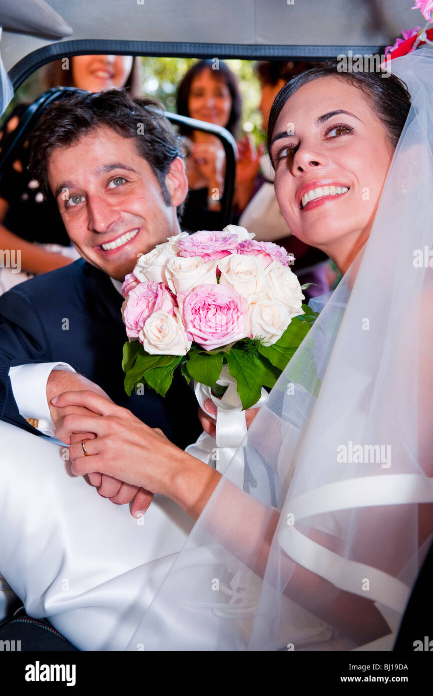 Braut und Bräutigam lächelnd in ein Auto Stockfoto