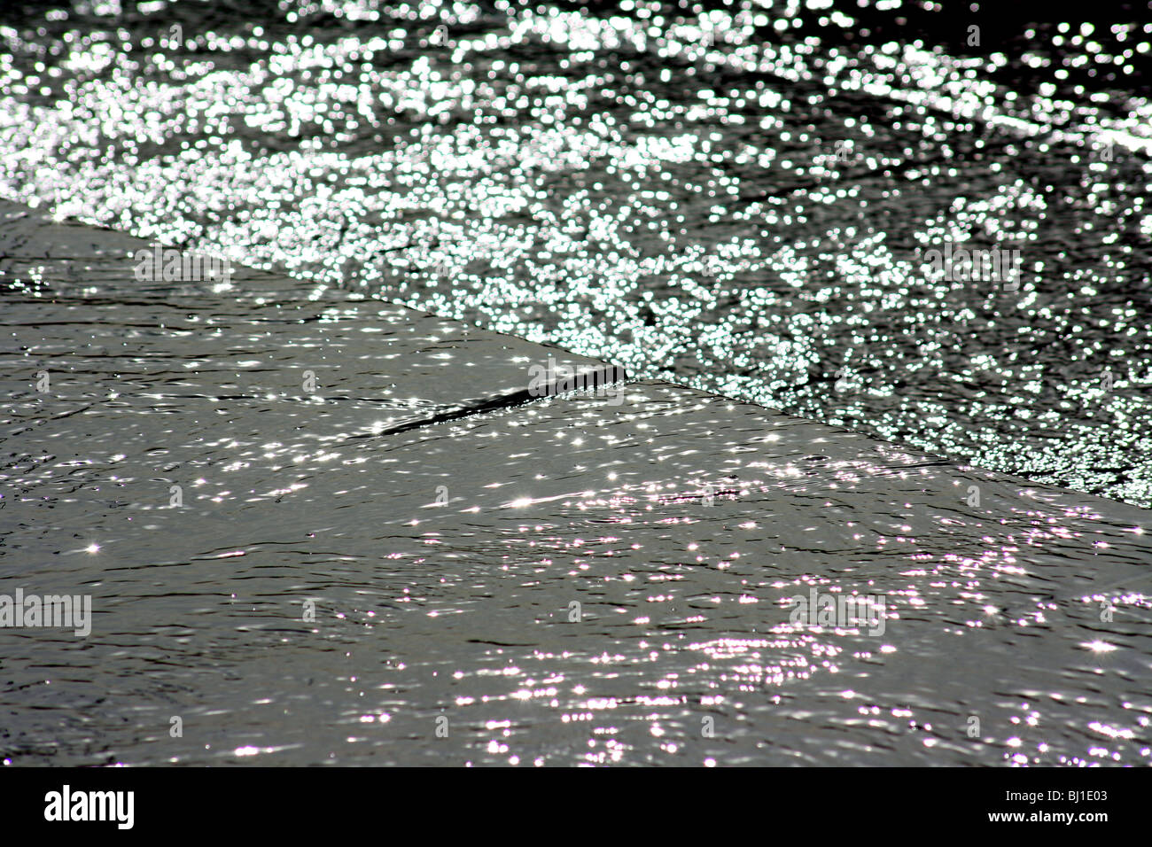 Wasser fließt über flachen Stein glitzert im Sonnenlicht Stockfoto