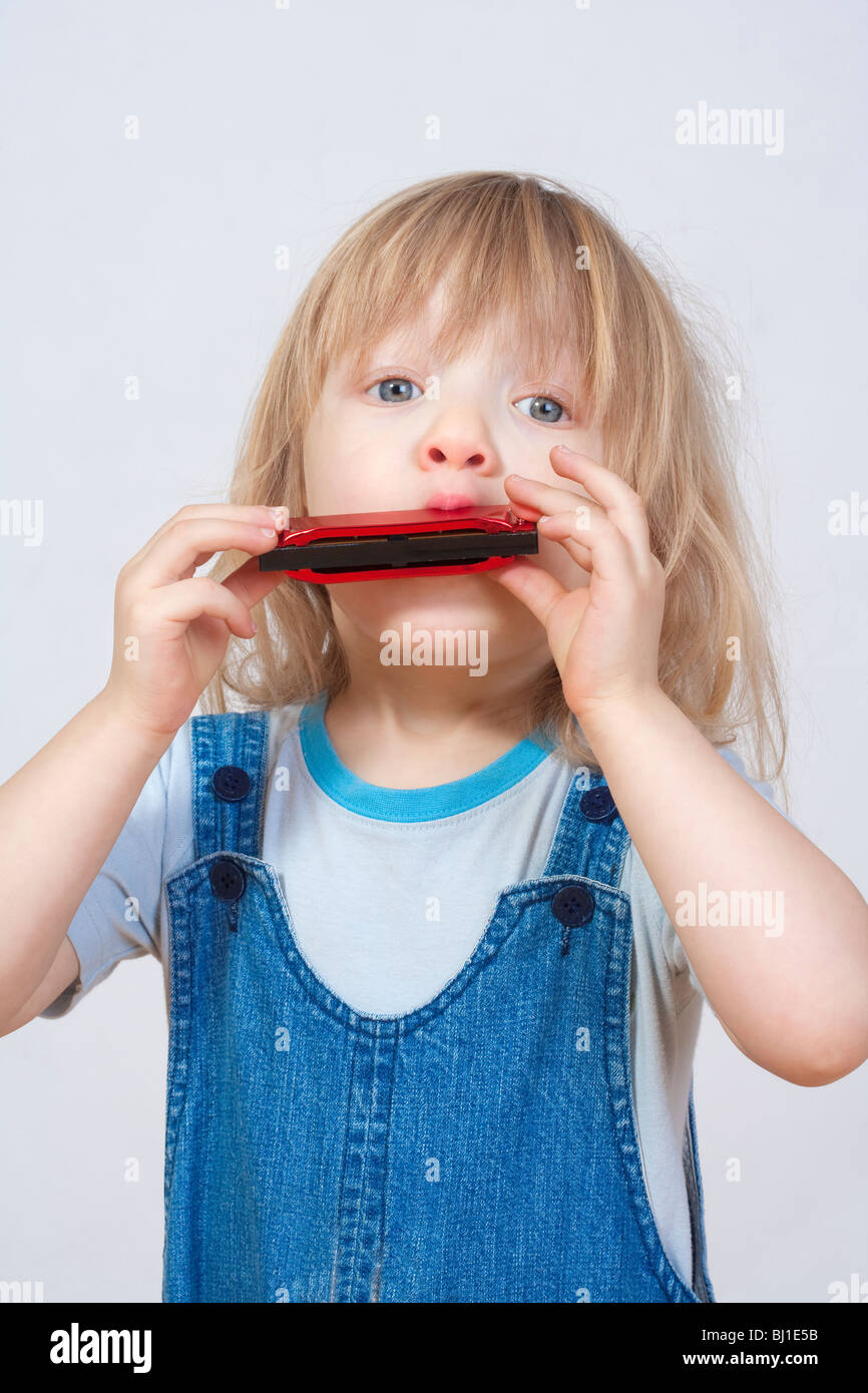 Junge mit langen blonden Haaren, die Mundharmonika spielen Stockfoto