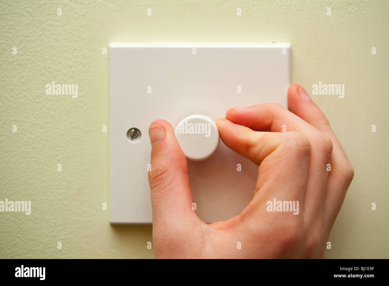 Ein MODEL Release Bild von jemandem aufdrehen der Licht-dimmer-Schalters im Vereinigten Königreich Stockfoto