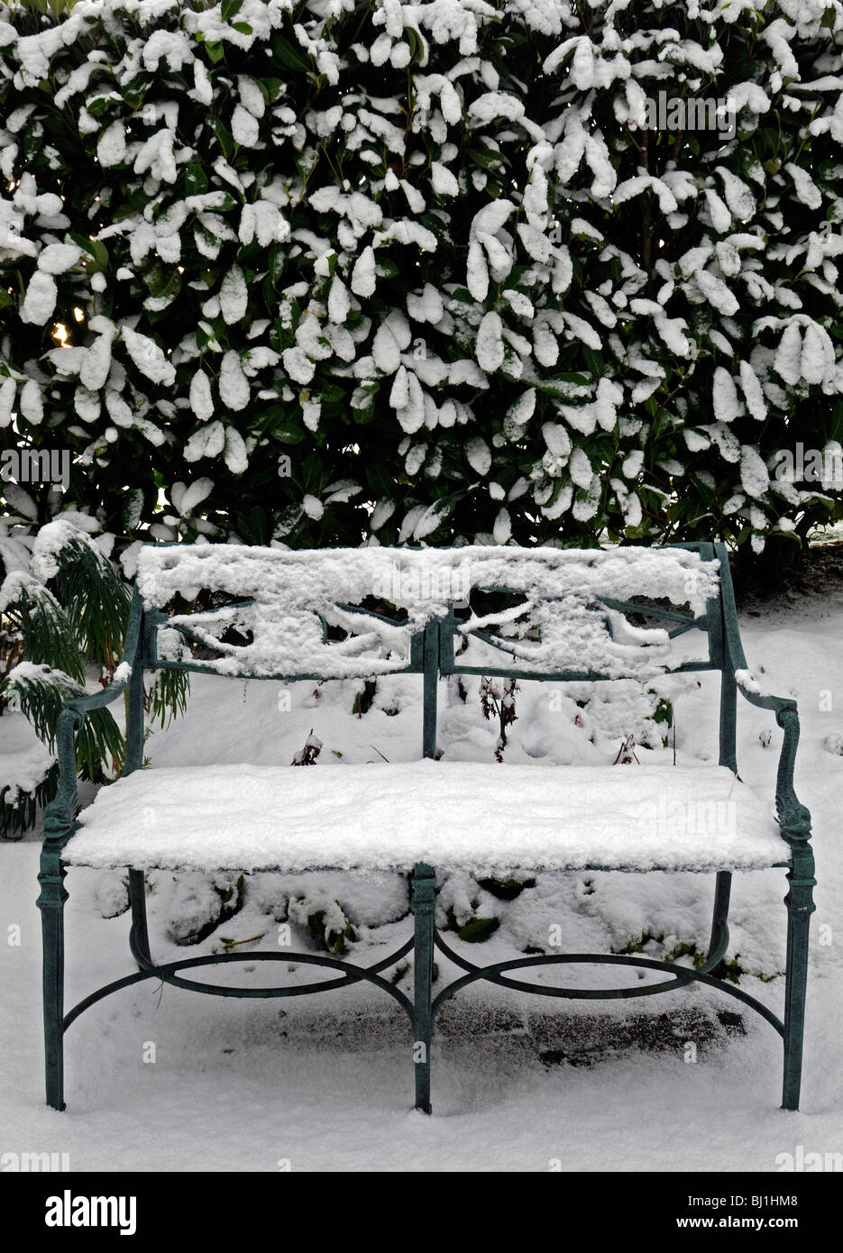 rustikale Schmiedeeisen Garten Tisch Sitzbezug bedeckt mit Schnee Winter Wunderland Gartenarbeit Szene szenische Stockfoto