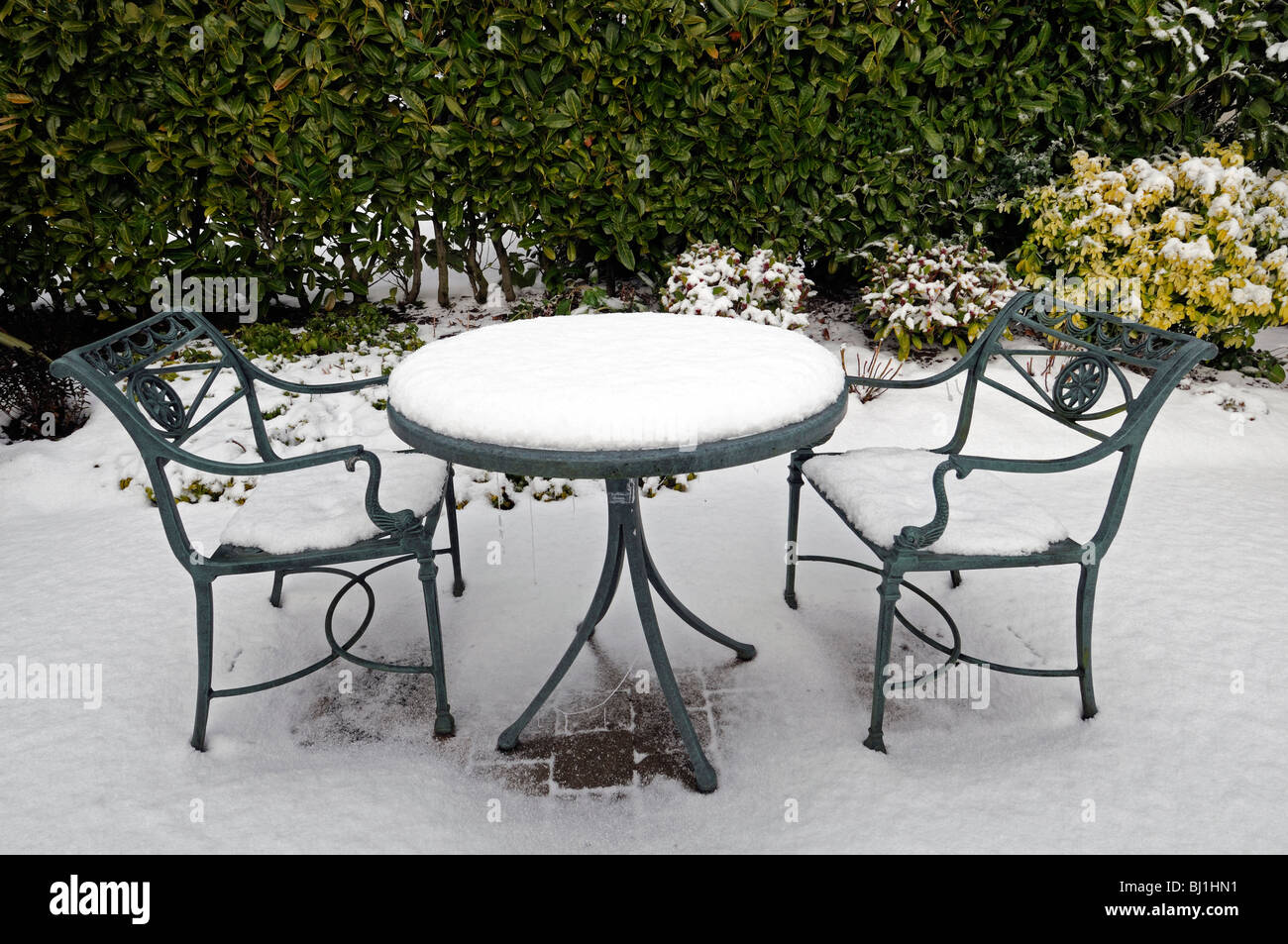 rustikale Schmiedeeisen Garten Tisch Sitzbezug bedeckt mit Schnee Winter Wunderland Gartenarbeit Szene szenische Stockfoto