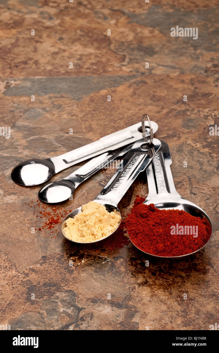 Messlöffel mit roten und gelben Gewürze auf einem Küchentisch Stockfoto