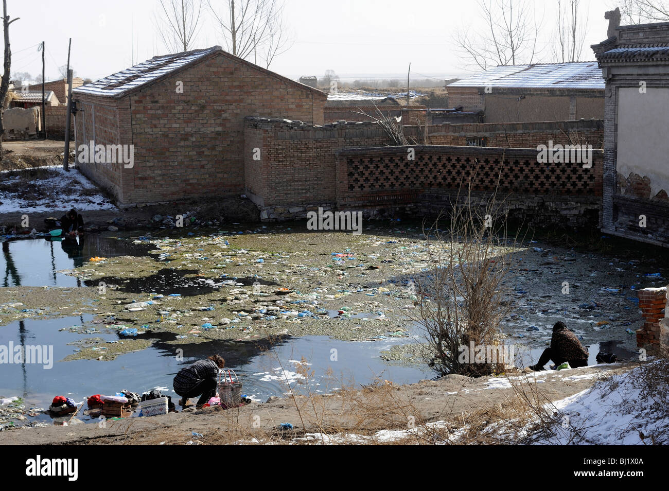 Frauen, die Wäsche in einem verschmutzten Teich in einem Dorf in der Provinz Hebei, China. 2. März 2010 Stockfoto