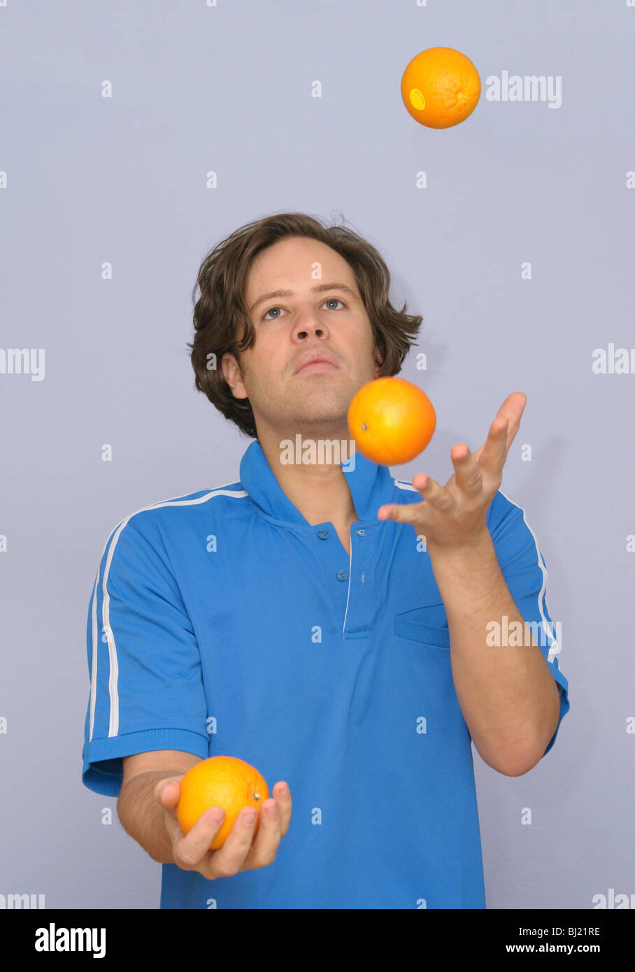 Junger attraktiver Mann Jonglieren mit Orangen oder multitasking Stockfoto