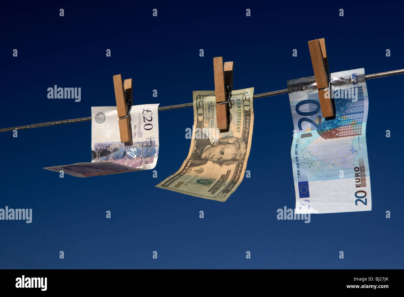 zwanzig Pfund-Dollar-Euro-Banknoten an eine Wäscheleine mit blauem Himmel hängen Stockfoto