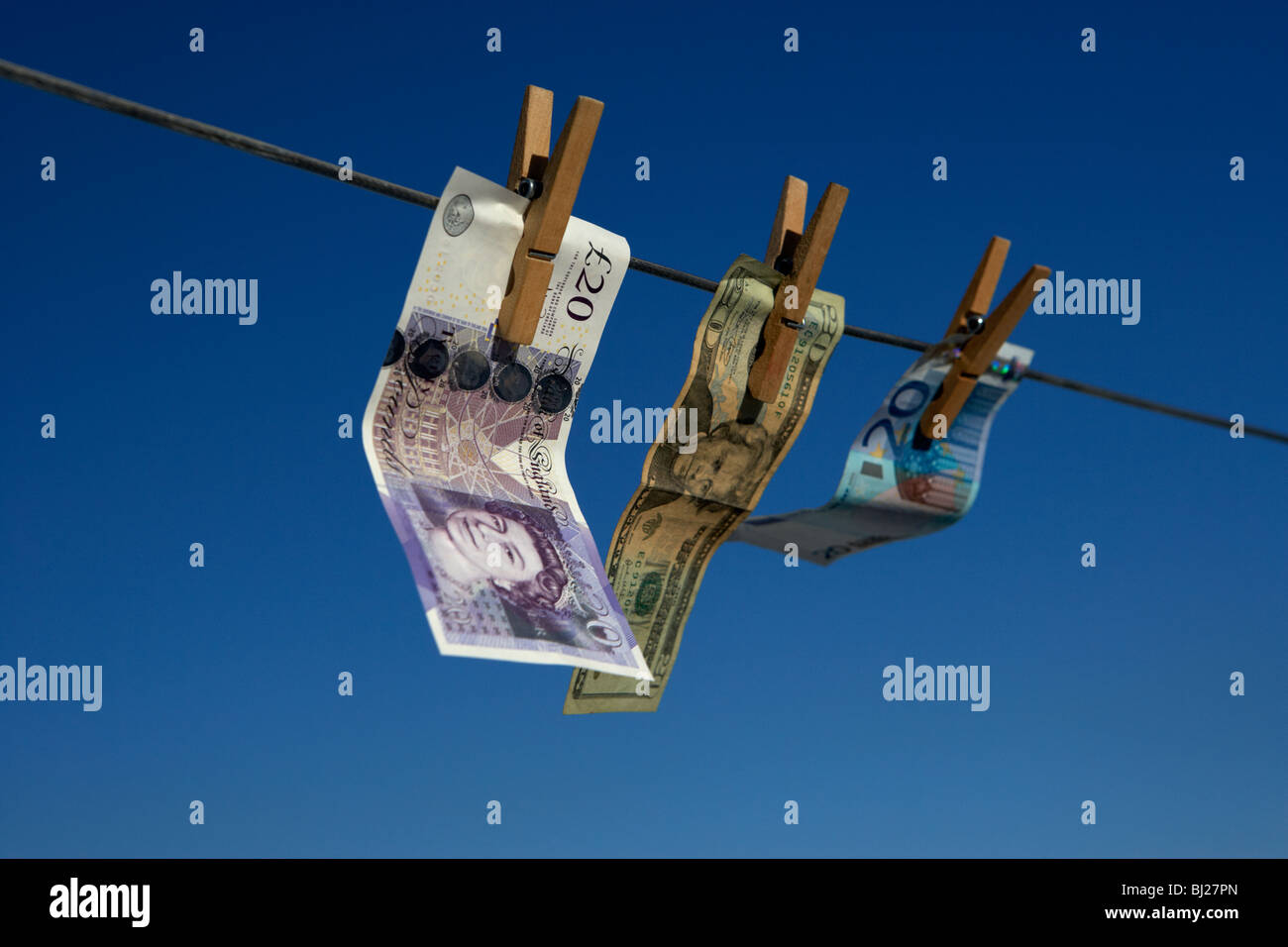 zwanzig Pfund-Dollar-Euro-Banknoten an eine Wäscheleine mit blauem Himmel hängen Stockfoto