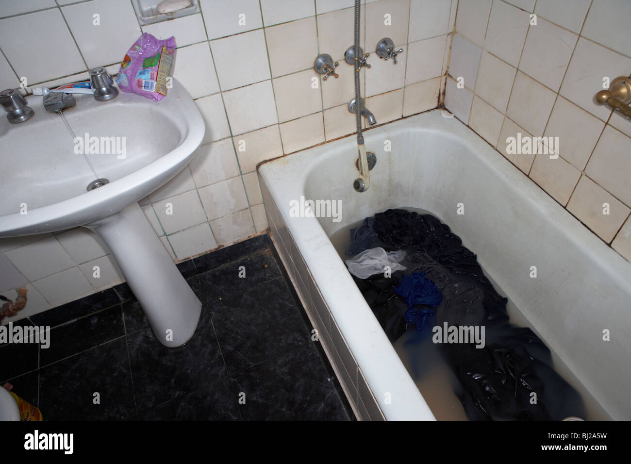 schmutzig, waschen in schmutziges Wasser in einer Badewanne gewaschen in einem heruntergekommenen Badezimmer Stockfoto