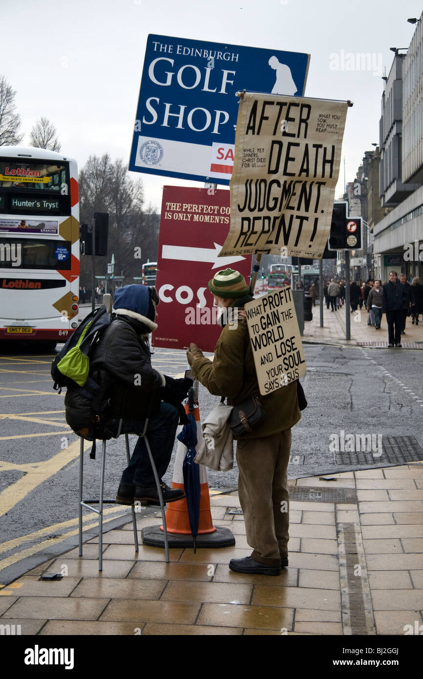 Ein Mann hält ein Plakat mit religiöse Zitate Debatten mit ein Mann hält ein Plakat Werbung auf Edinburgh Princes Street Stockfoto