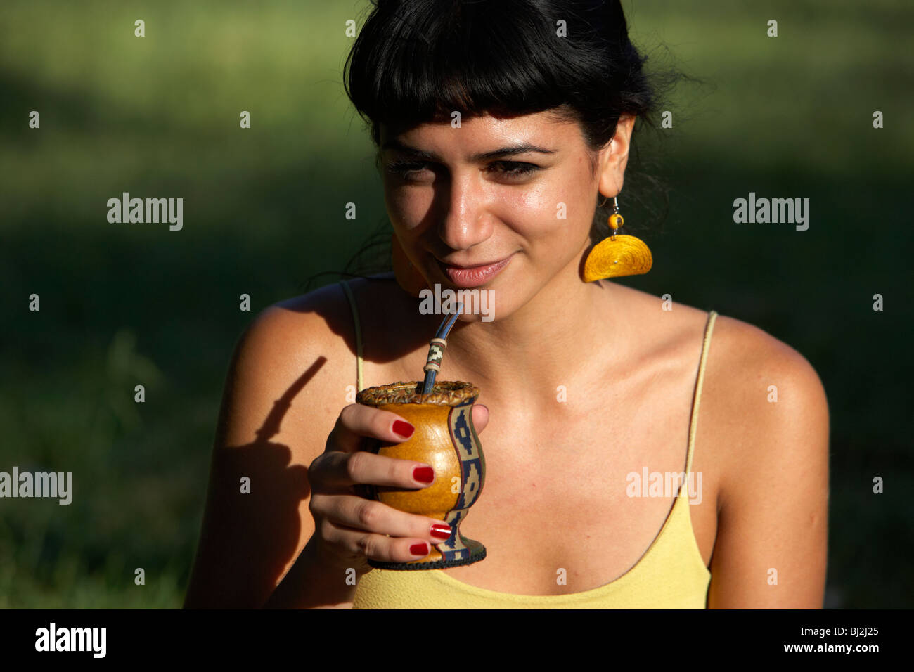 junge spanische Latin Frau trinken Yerba Mate aus einem Kürbis in den Park in Buenos Aires Argentinien Stockfoto