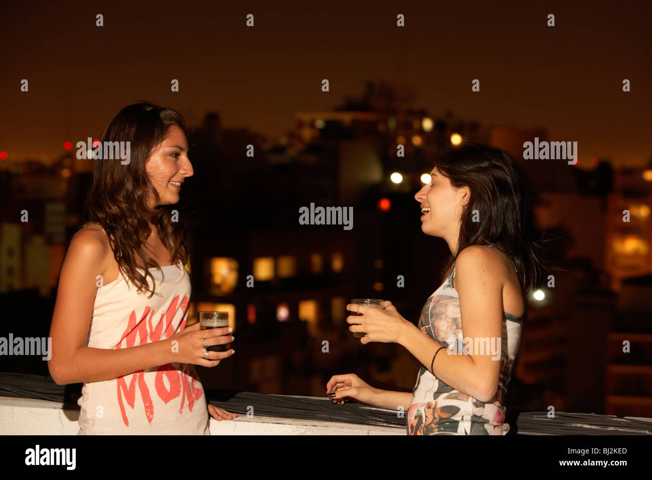 zwei junge spanische Latin Frauen Bier trinken und Lachen auf einem Balkon Party in Buenos Aires Argentinien Stockfoto