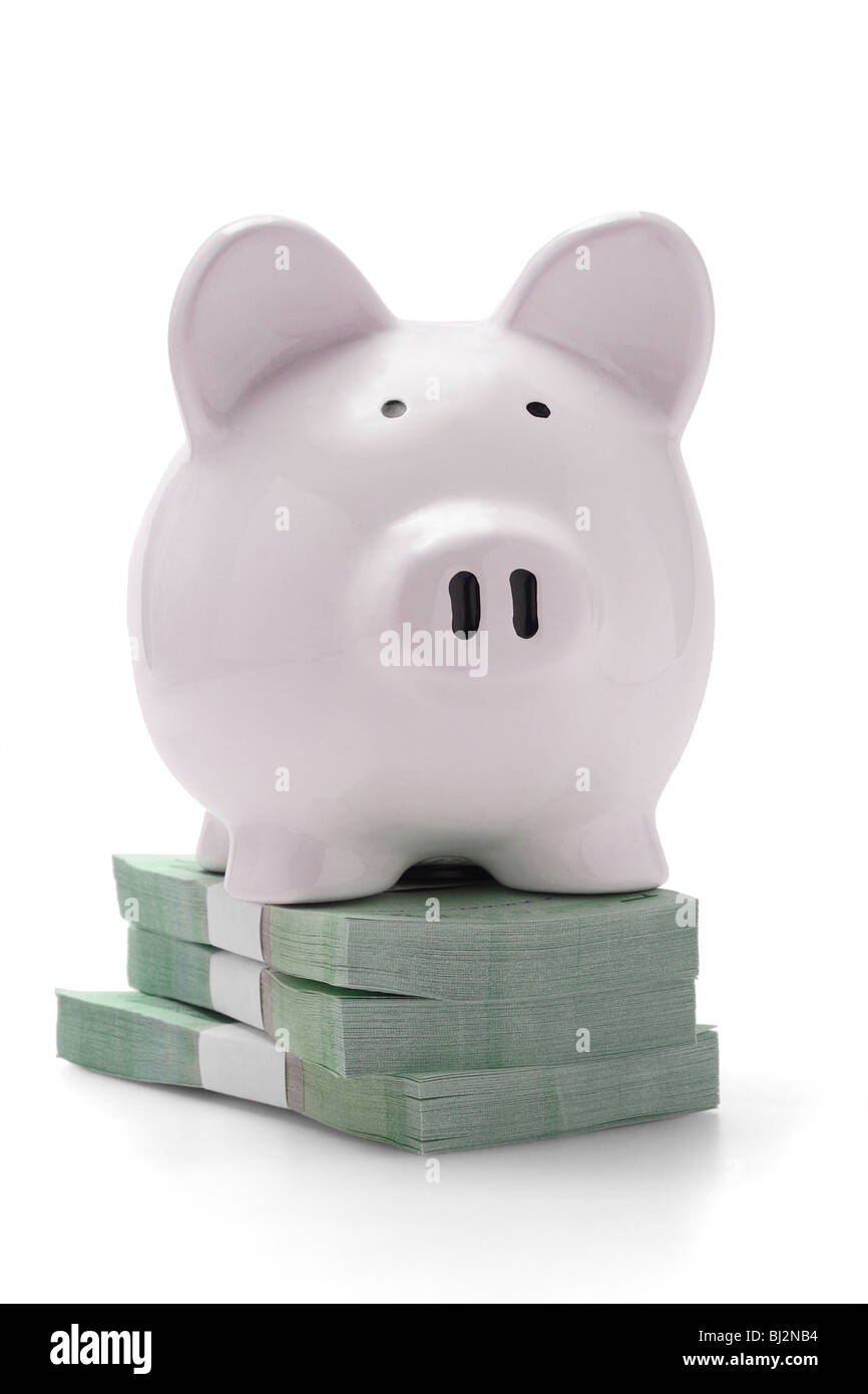 Sparschwein auf Stapel von Geld auf weißem Hintergrund Stockfoto