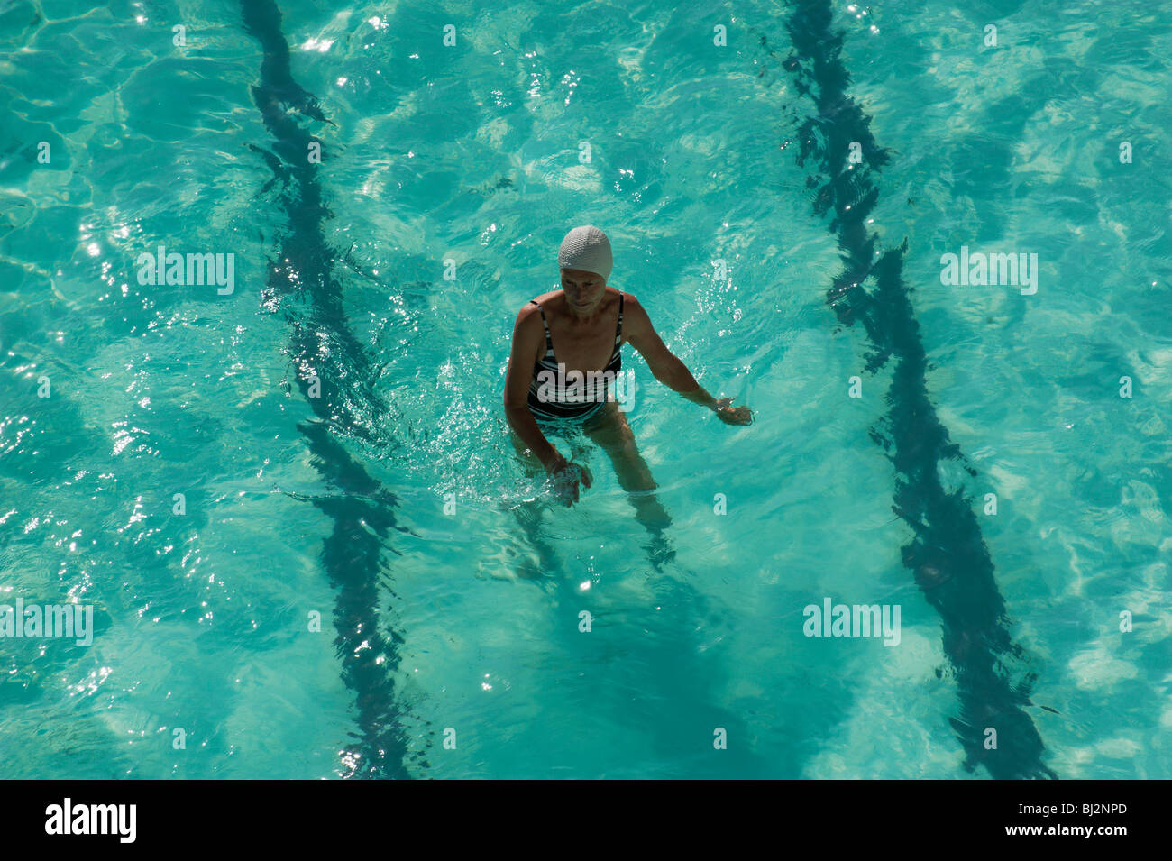 Eine ältere Frau geht in einem Pool für die Übung an einem Ozeanbecken Bondi Icebergs am Bondi Beach, Sydney, Australien Stockfoto