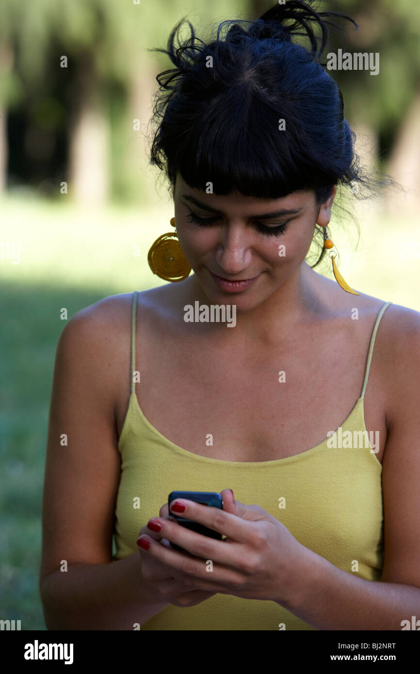 junge spanische Latin Frau senden oder lesen eine SMS-Nachricht auf ihr Handy im Park in Buenos Aires Argentinien Stockfoto