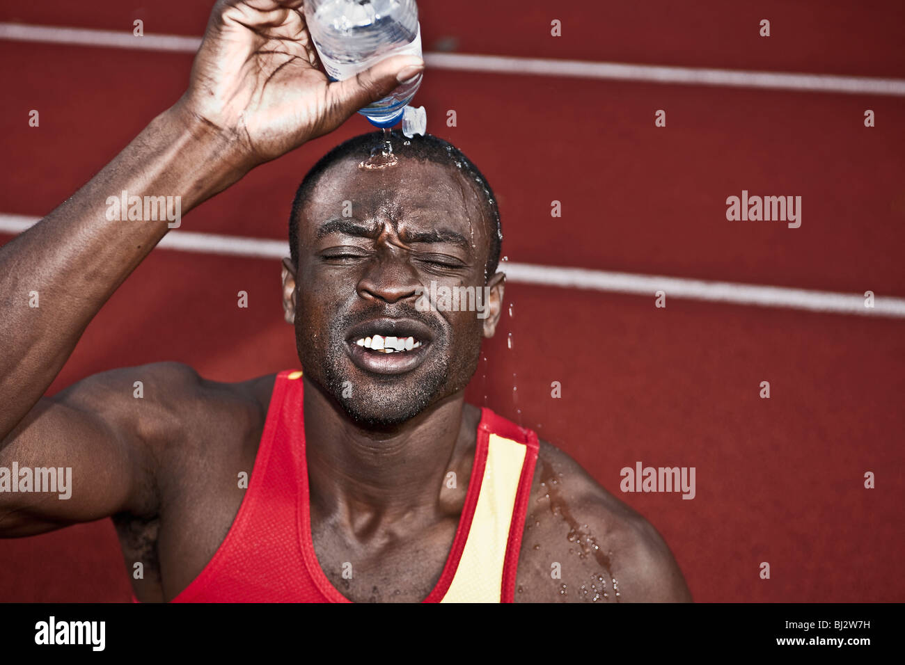 männlicher Athlet gießt Wasser über den Kopf Stockfoto