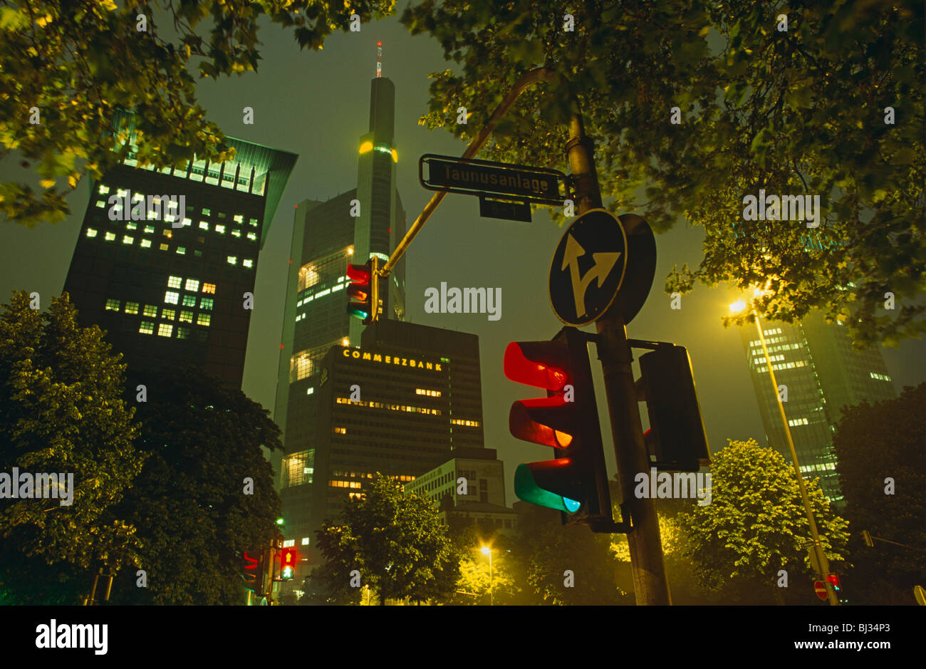 Durch eine Lücke in den Bäumen und Ampeln ist der riesige Wolkenkratzer Büroturm der Commerzbank. Stockfoto