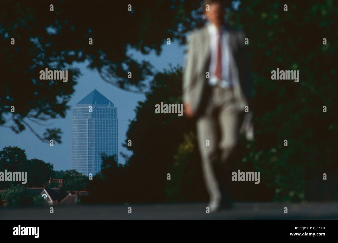 Als ob entlassen, verschwindet ein Geschäftsmann mit einer Aktentasche in die entgegengesetzte Richtung zum Canary Wharf tower Stockfoto