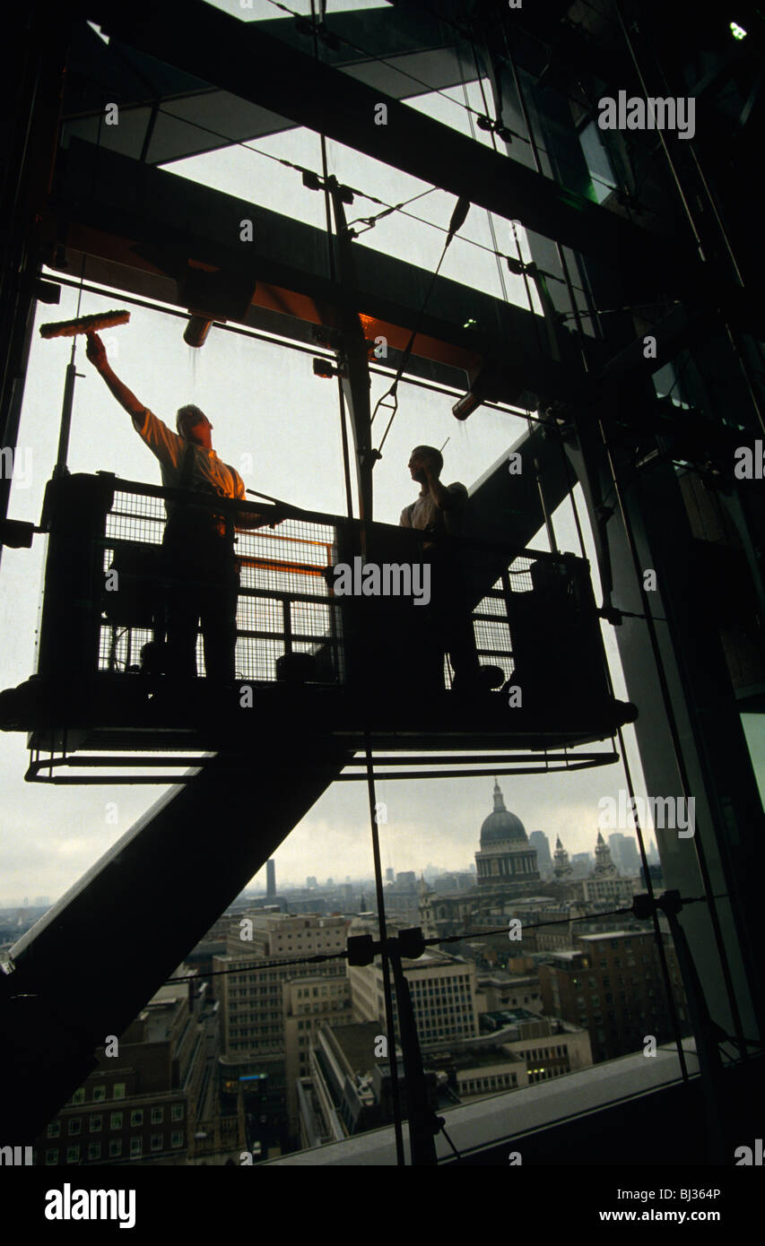 Zwei Fensterreiniger sicher befestigt an einer äußeren Wiege waschen die großen Glasscheiben an einem Gebäude bei Broadgate Stockfoto
