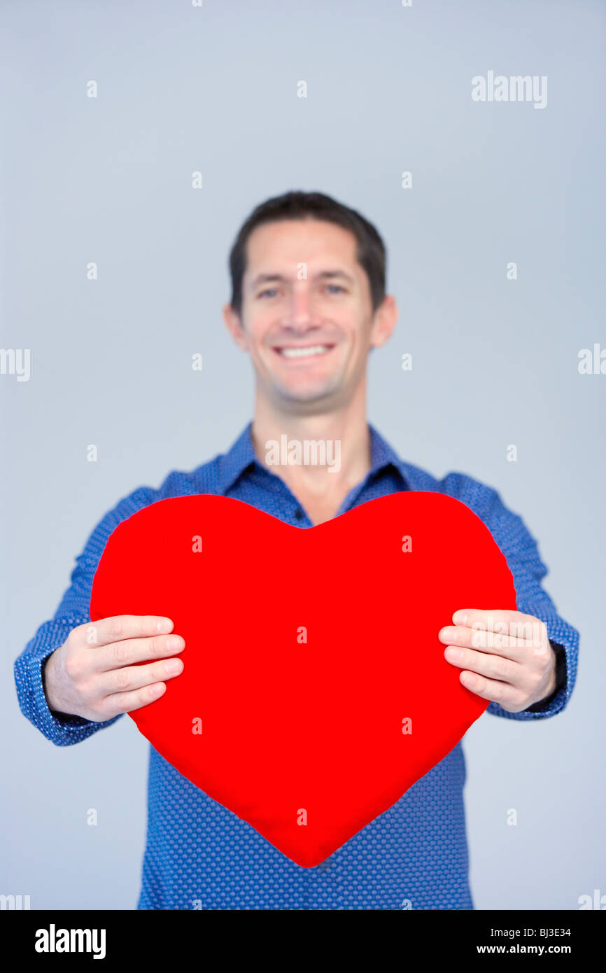 lächelnder Mann zeigt ein großes rotes Herz Stockfoto