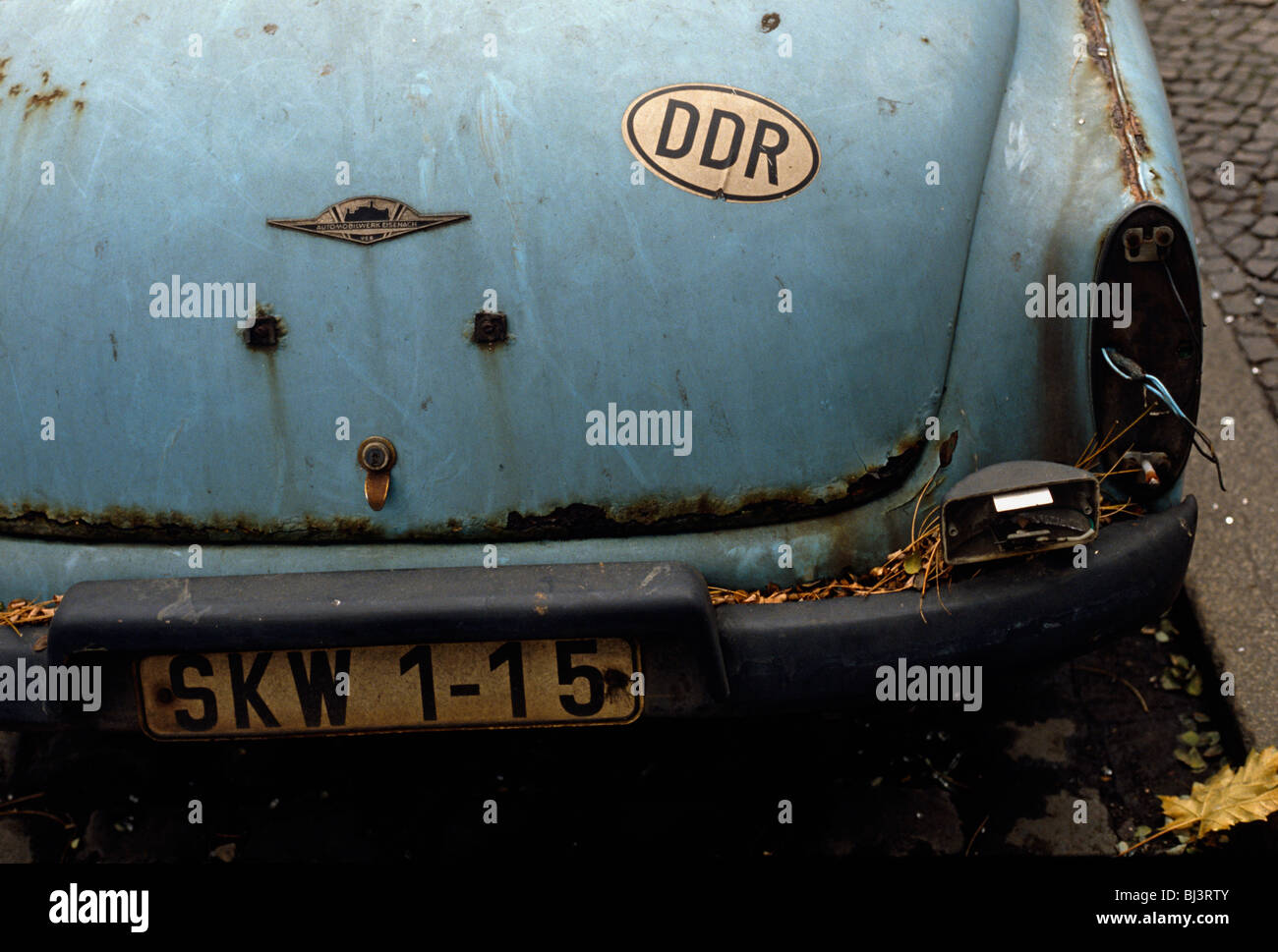 Detail von einem rostigen Auto Wartburg 312 an der Bordsteinkante in einen östlichen Berliner Bezirk. Ein Aufkleber mit den Buchstaben DDR. Stockfoto