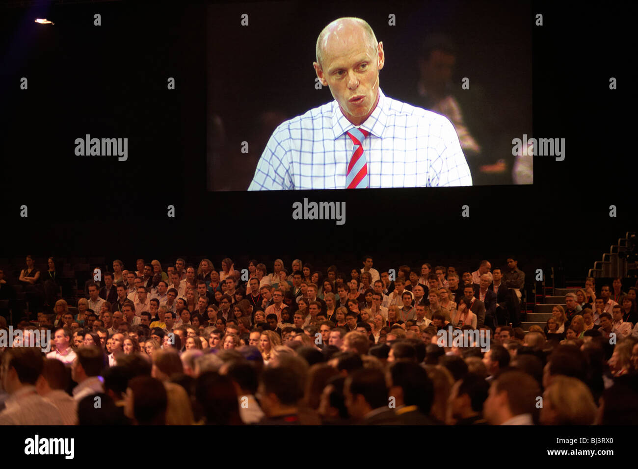 Vorstandsvorsitzender Ernst & Young Mark Ottey blickt hinunter auf seine Mitarbeiter auf einer riesigen Leinwand Adressierung seine loyale Mitarbeiter. Stockfoto