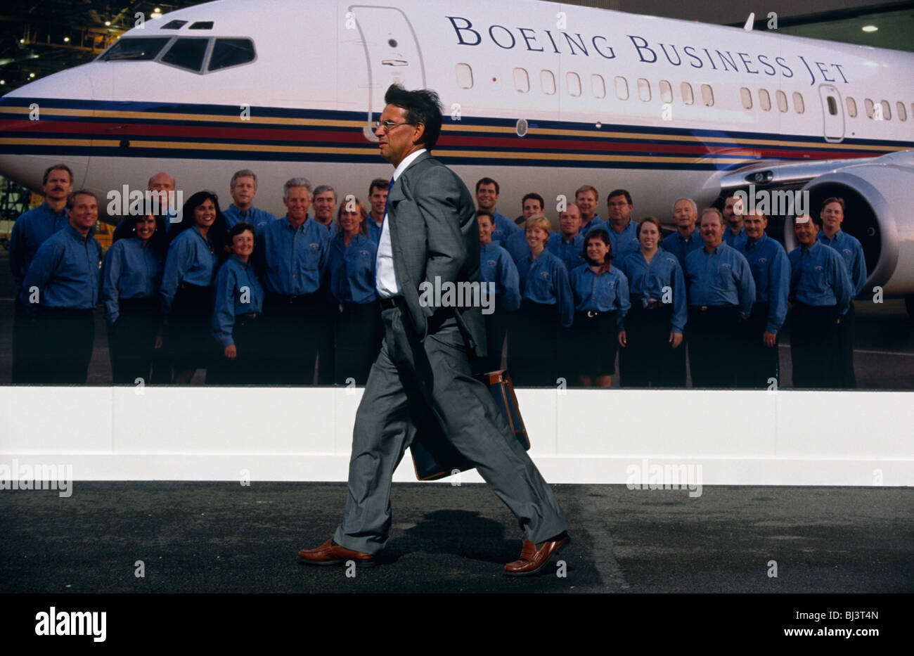 Ein Geschäftsmann eilt vorbei Boeing Firma Werbung Riesenposter während der Farnborough Air Show, England. Stockfoto