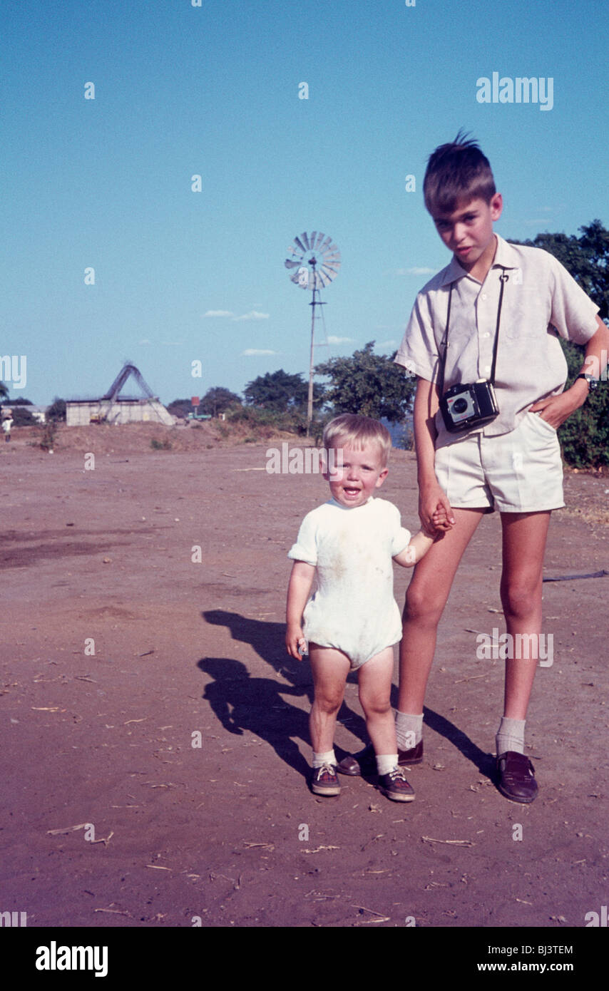 Ein junger Bursche von 10 Posen für ein Porträt von seinem Bruder genommen, während an der Hand seines jungen Neffen. Stockfoto
