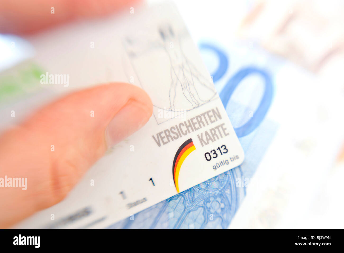 Hand hält eine Krankenversicherungskarte über einige Euro-Scheine Stockfoto